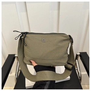 Detail of olive green nylon crossbody bag with silver flower logo and wide woven strap
