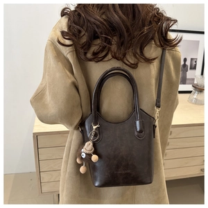 Detail of dark brown faux leather bucket bag with plush monkey charm and fashion lettering
