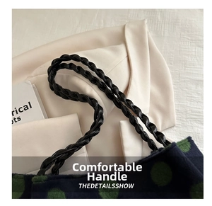 Détail de la poignée en cuir noir tressé sur un sac cabas en laine bleu à pois verts