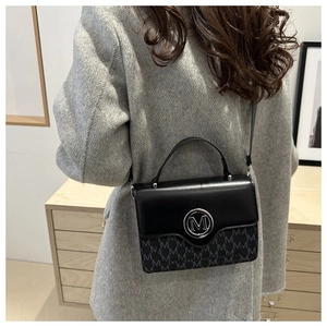 Detailed view of women's crossbody bag with black leather and silver 'M' logo buckle