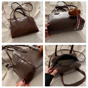 Detail view of brown PU leather Boston bag with embossed text and bear charm accessory