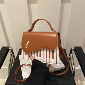Chic piano note crossbody bag with brown flap and gold treble clef clasp on books
