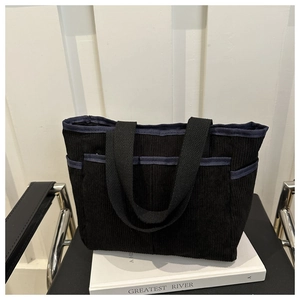 Detail of vintage black corduroy tote bag showing front pockets and durable canvas straps