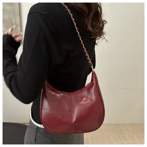 Model wearing dark red crescent underarm bag with gold chain and smooth leather finish