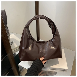 Sac hobo marron foncé en cuir brillant de forme croissant posé sur un miroir