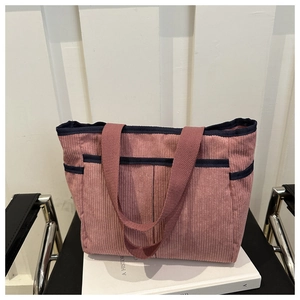 Close-up of pink corduroy tote bag featuring blue contrast binding and ribbed texture