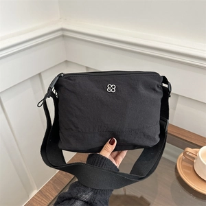 Minimalist black nylon crossbody bag with floral silver buckle and adjustable strap