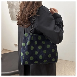 Detail of the green polka dot plush tote bag with a black woven chain shoulder strap