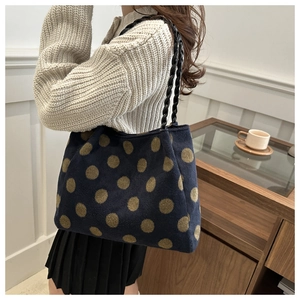 Detail of navy polka dot wool tote bag with black woven leather shoulder strap
