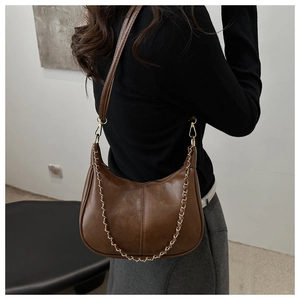 Detail view of the brown leather shoulder bag featuring a vintage gold chain and stitching