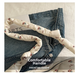 Detail of soft quilted handles and floral embroidery on a white canvas cloud bag