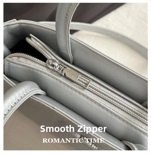 Close-up of smooth metal zipper and premium textured leather on the grey bucket bag