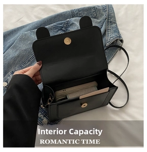 Internal view of minimalist black square bag showing storage space for phone and cards
