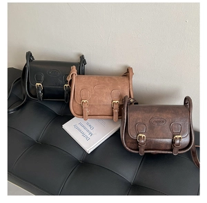 Three retro saddle bags in black, light brown, and caramel leather on a bench