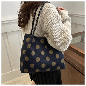 Detail of dark blue tote bag with gold polka dots and black woven shoulder straps
