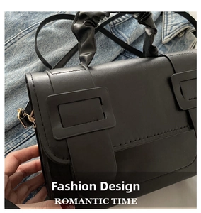 Detail of a black faux leather handbag with pleated handle and large square buckle