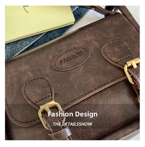 Detail of retro brown leather crossbody bag with FASHION logo and gold metal buckles