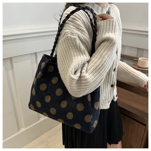 Detail view of navy tote bag with large brown polka dots and black woven handles