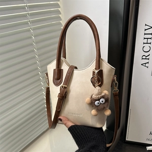 Borsa a secchiello crema e marrone con ciondolo mostro e tracolla regolabile versatile