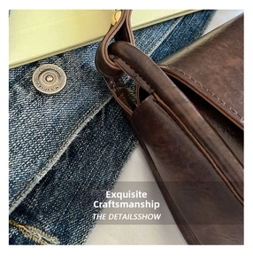 Macro detail of dark brown leather satchel with oil-wax texture and precise stitching