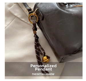 Close-up of oil-waxed leather texture with vintage gold ring and braided bell charm