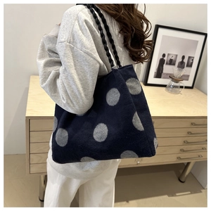 Detail of navy knit tote bag with large grey polka dots and black woven strap