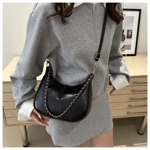 Detail of black semi-moon bag with elegant gold chain strap and smooth leather texture