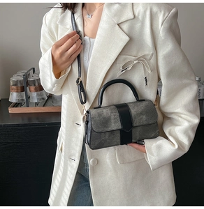 Detail of grey matte texture crossbody bag with black leather straps and gold buckle