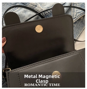 Close-up of a premium gold magnetic clasp on a black textured faux leather crossbody bag