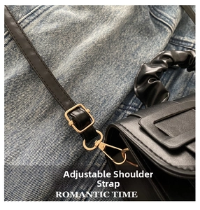 Detail of adjustable leather strap with gold metal buckle on a black shoulder bag