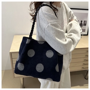 Close-up of soft plush tote bag with navy blue polka dots and woven black handles