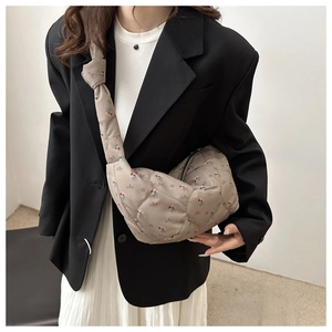 Quilted dumpling bag with floral print and knot shoulder strap detail shown on model