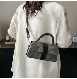 Detail of gray frosted fabric and black leather stitching on a retro crossbody bag