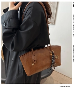 Détail du sac cabas vintage en cuir marron avec pendentifs raquette de tennis et clé