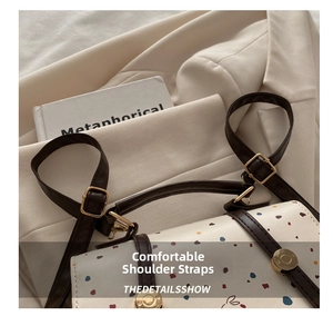 Close-up of cream handbag with bunny illustrations and gold hardware details