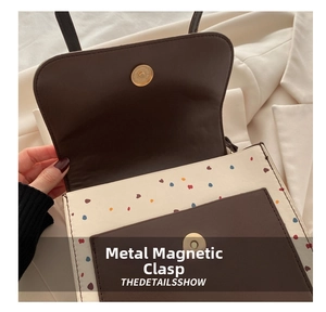 Close-up of the secure hardware magnetic snap closure on the cream and brown backpack