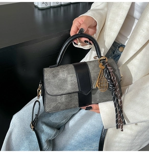 Detail of grey washed crossbody bag with tennis racket pendant and tassel decoration
