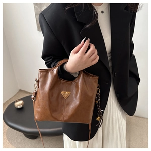 Brown faux leather tote bag with gold triangle logo and silk scarf on black blazer