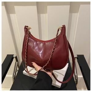 Detail of burgundy leather hobo bag with gold chain strap and smooth glossy finish