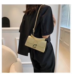 Detail of champagne gold leather shoulder bag with round lock worn over a black outfit