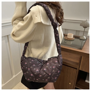 Détail du sac demi-lune matelassé avec motif floral et bandoulière nouée à l'épaule