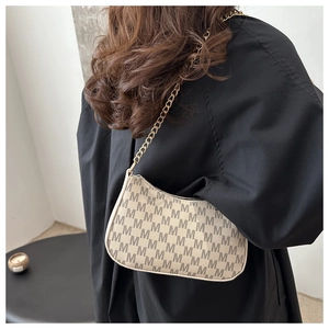 Detail of small crossbody bag featuring golden chain strap and monogram patterns
