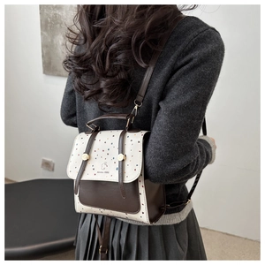 Detail of the colorful polka dot flap and bunny logo on a brown leather mini backpack