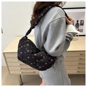 Detail of black quilted dumpling bag with floral prints and knotted shoulder strap