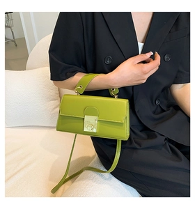 Detail view of avocado green crossbody bag with gold square buckle on a black blazer