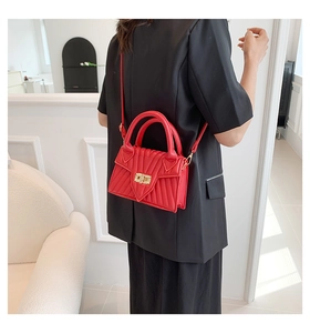 Detail der roten Stepptasche mit goldenem Schloss und elegantem V-förmigem Nahtmuster
