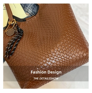 Detail shot of textured dark brown woven faux leather tote bag with metallic charm