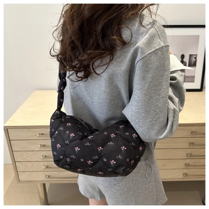 Detailed shot of a black quilted nylon shoulder bag with pink floral and letter prints