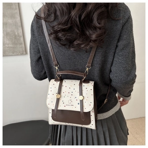 Rear view of a retro college-style mini backpack in cream and brown with thin leather straps