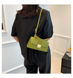 Detail of avocado green leather handbag with gold metal clasp and curved top handle